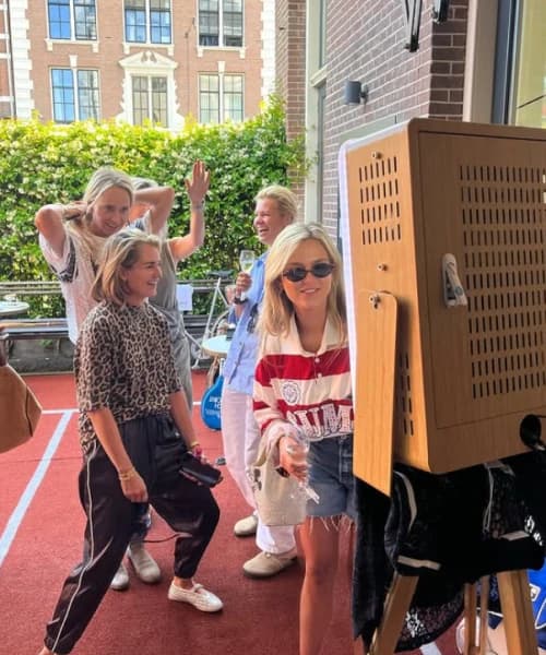Gasten lachen bij de fotobooth op een dakterras in Amsterdam